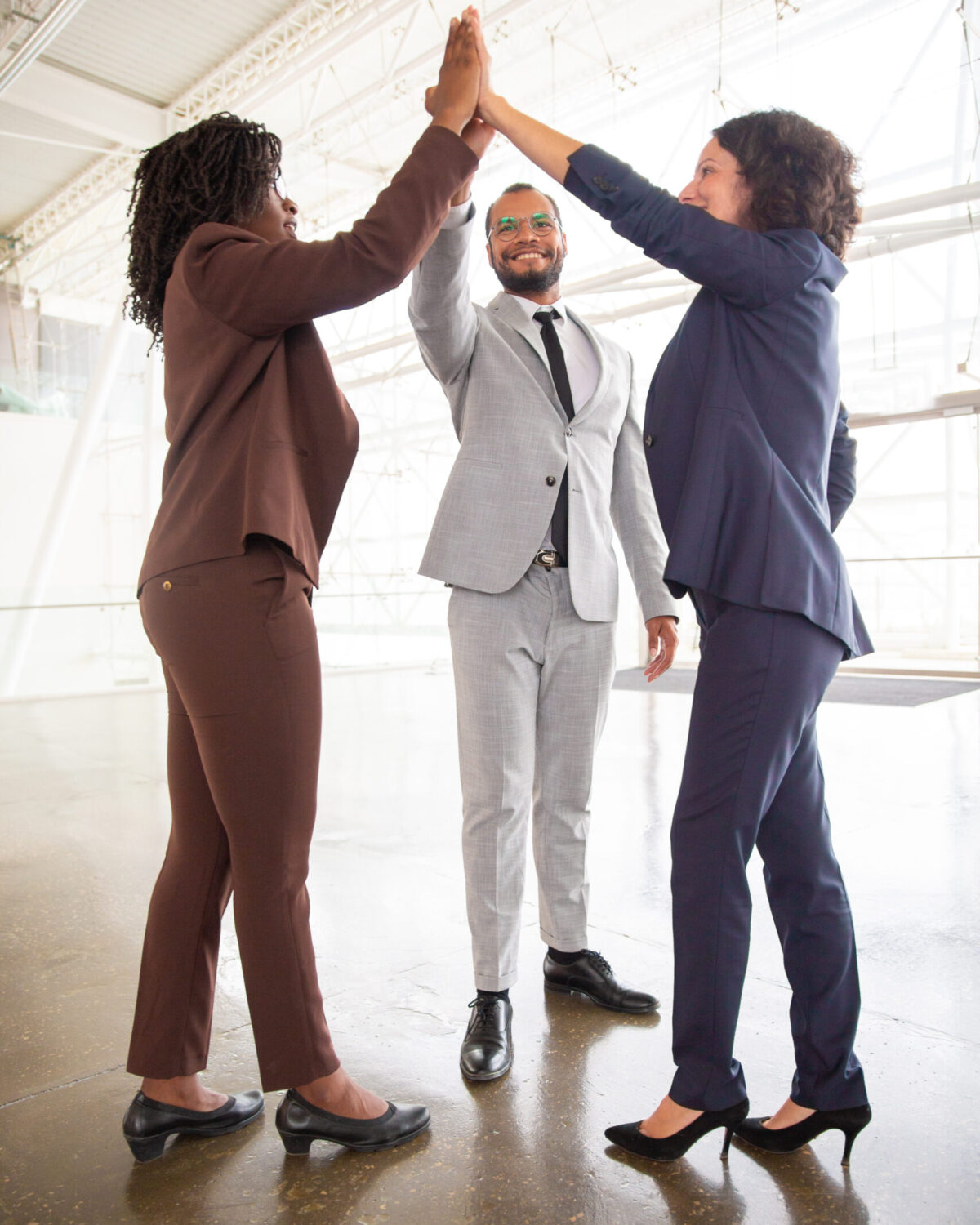 Business team giving high five. Full length view of cheerful multiethnic business colleagues celebrating success, full length view. Teamwork concept